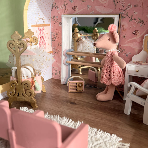 Inside the ballerina suitcase dollhouse: ballet barre with mirror, ballerina mouse, tutu on a gold stand and pink theatre seats