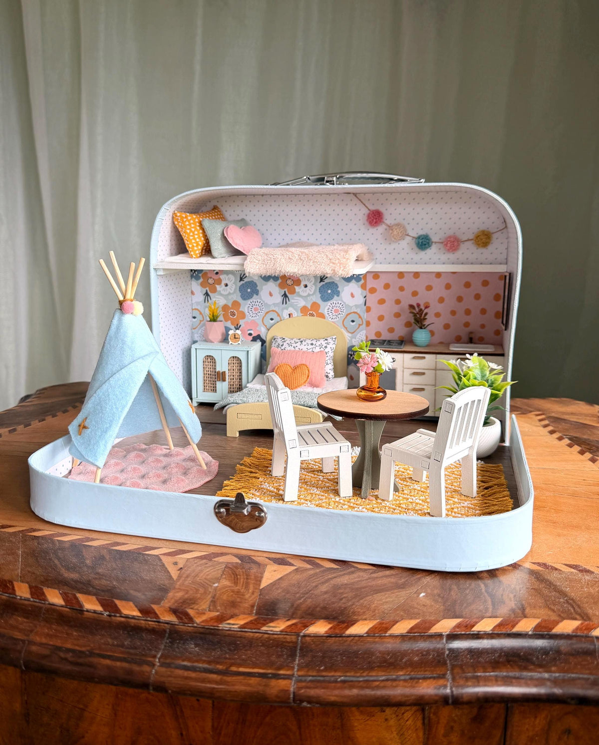 Happy Nest medium suitcase dollhouse with a play teepee, garland, round dining table and sleeping loft